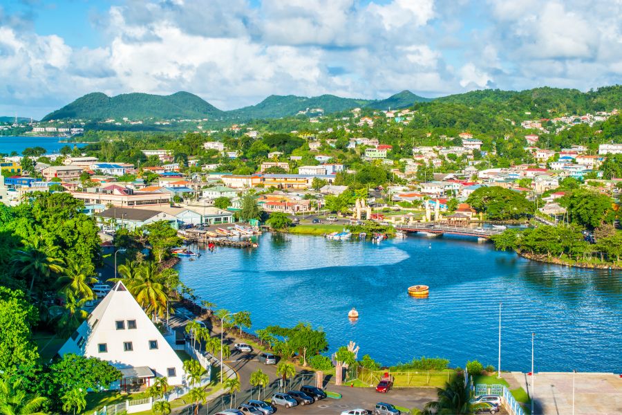 Picture of st lucia, colourful buildings and lake surrounded by mountains 
